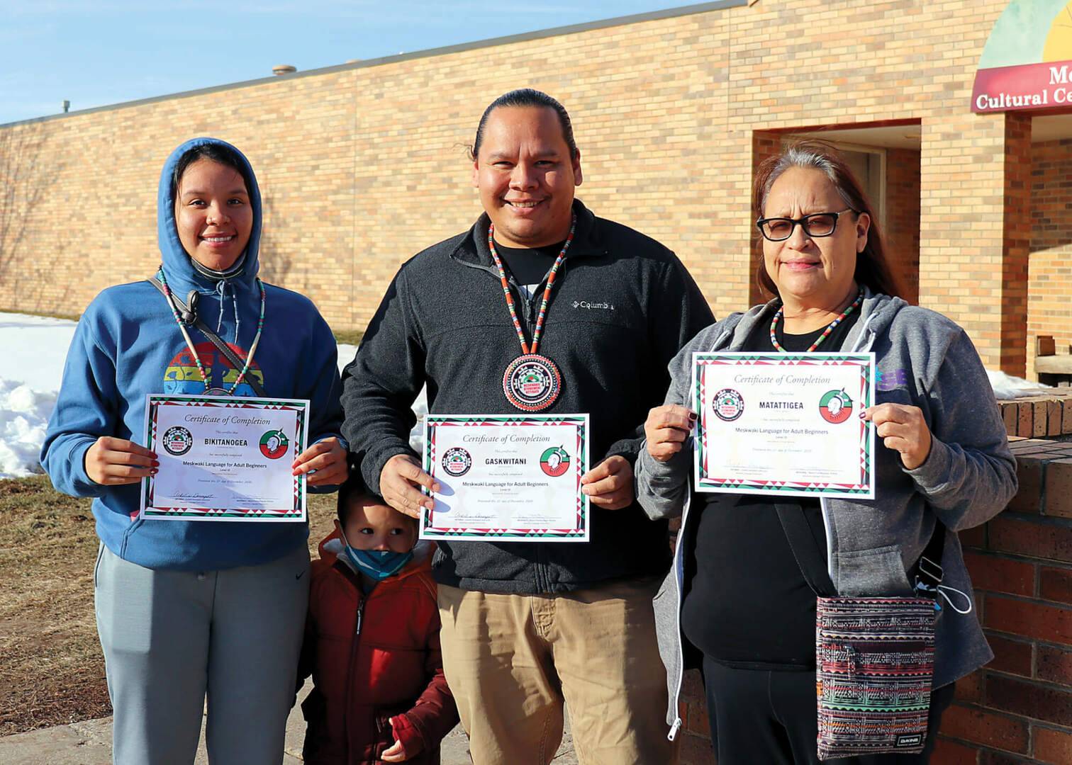 Three people hold certificates from the Language Department