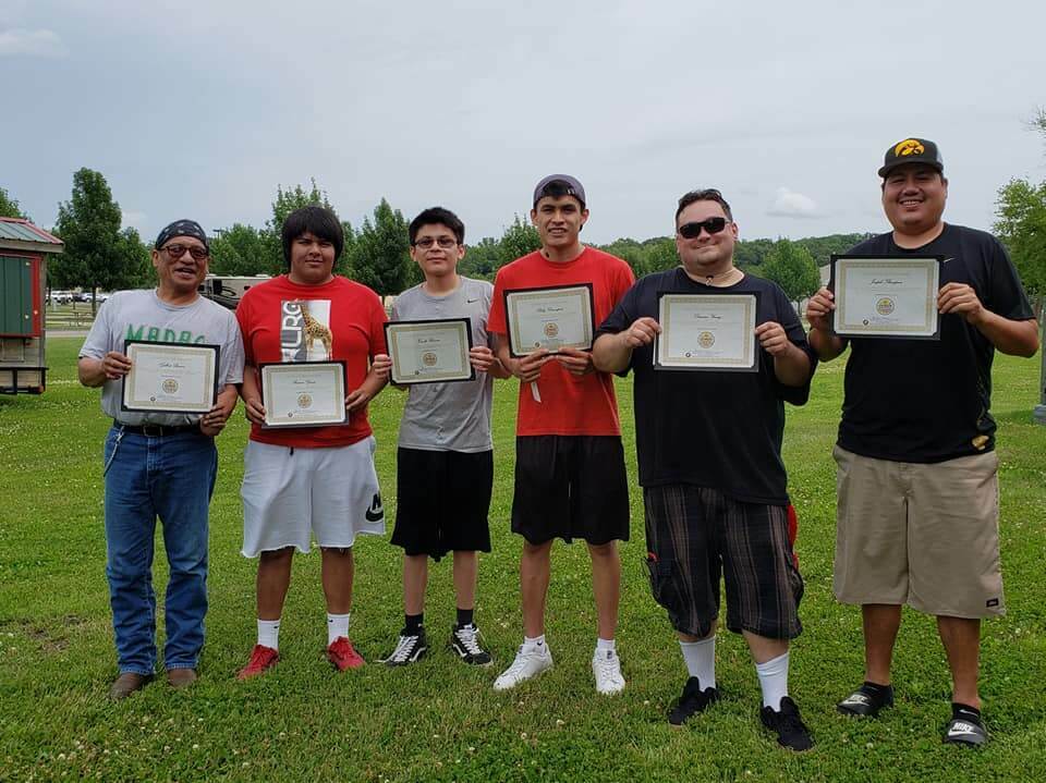 Men standing in a line holding up certificates