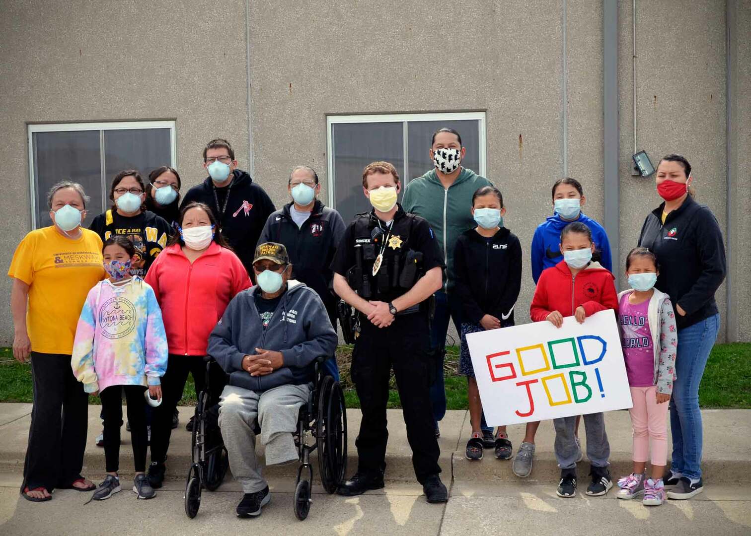 A group of people in masks with a Meskwaki Police Officer and a Good Job sign