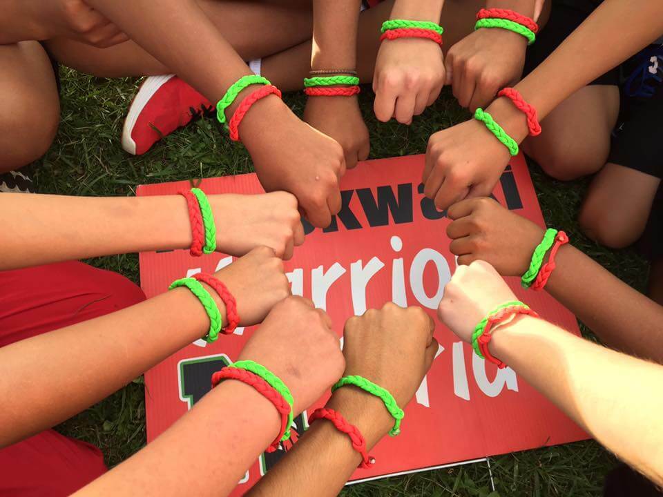 Kids putting their wrists in a circle to show their warrior pride bracelets